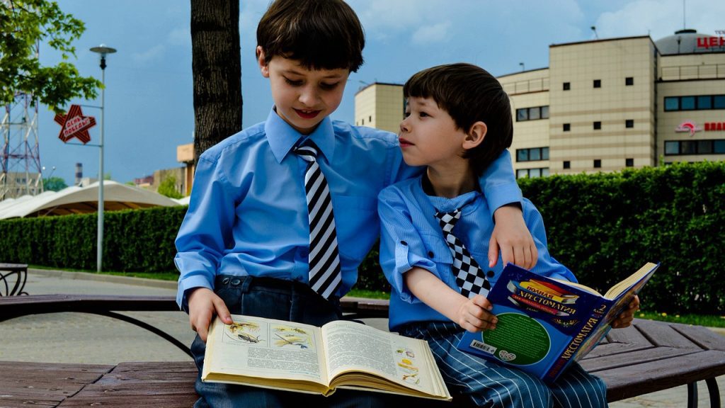 Про новую школу, два мальчика сидят на лавке в школьной форме и читают книги.