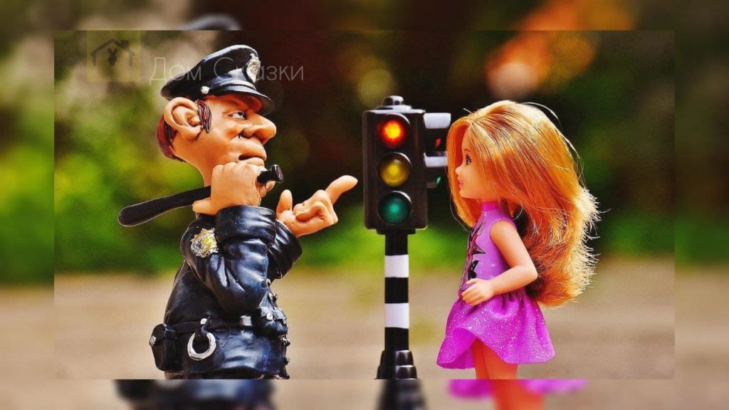Игрушки, одна полицейский, вторая девушка с рыжими волосами, полицейский показывает дорогу у рядом стоящего светофора.