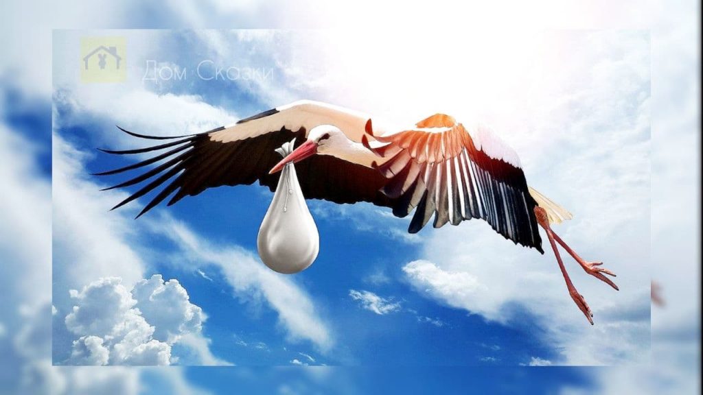 Аист с большими крыльями летит в чистом голубом небе с голубыми облаками, в клюве у него белый тряпичный мешочек.