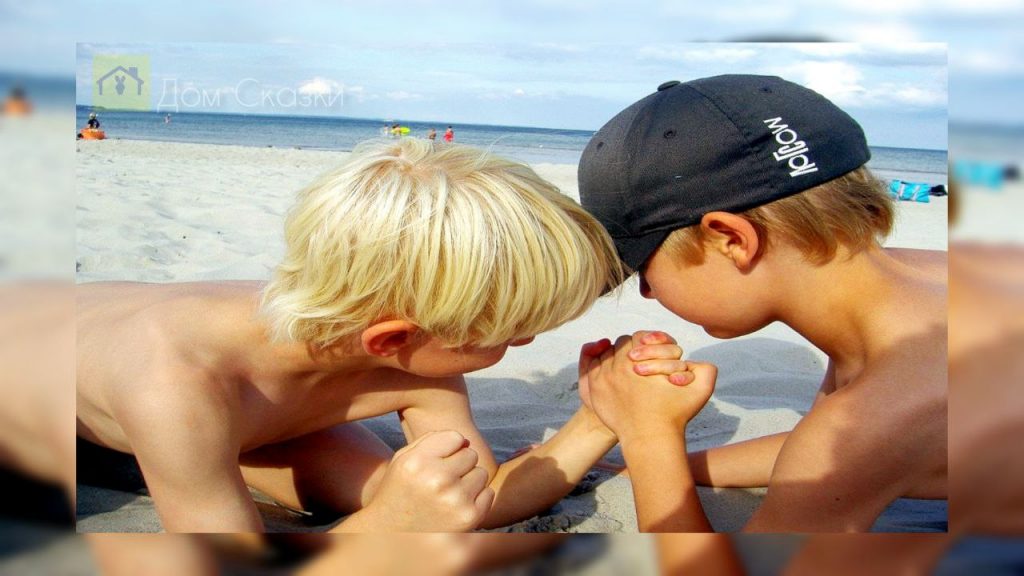 Кто круче, два мальчика на пляже меряются силами борясь на руках.